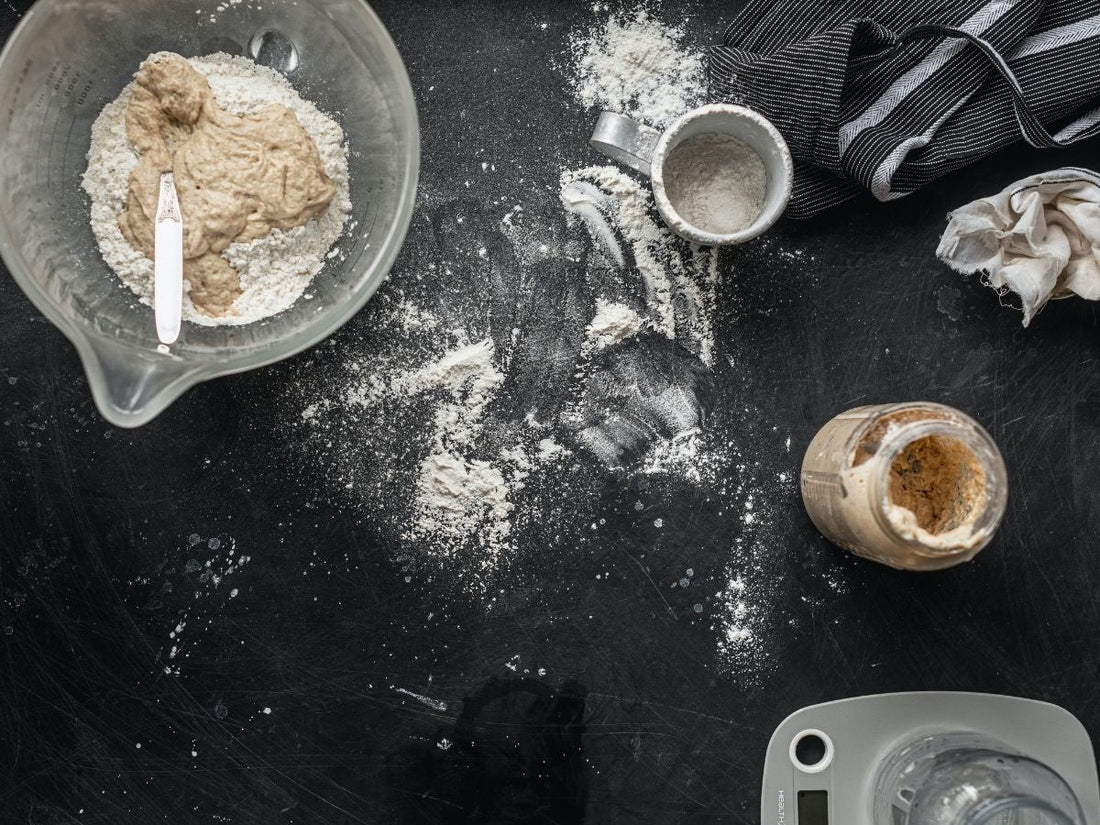 Floured countertop with starter, dough, and baking tools